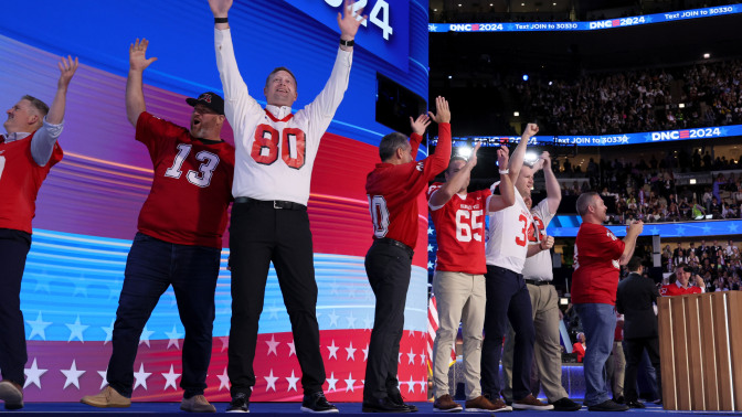 grown men in football jerseys on the DNC stage, all former players for Tim Walz