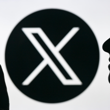 X logo behind user on smartphone