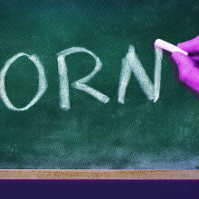 A hand writes the word 'porn' in block capitals in chalk on a blackboard
