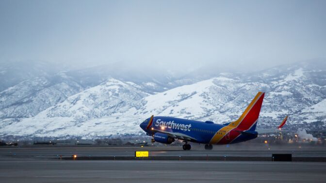 a southwest airplane take off from the runway with snow-capped mountains in the background