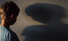 A boy looks at his shadow on a wall.