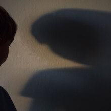 A boy looks at his shadow on a wall.