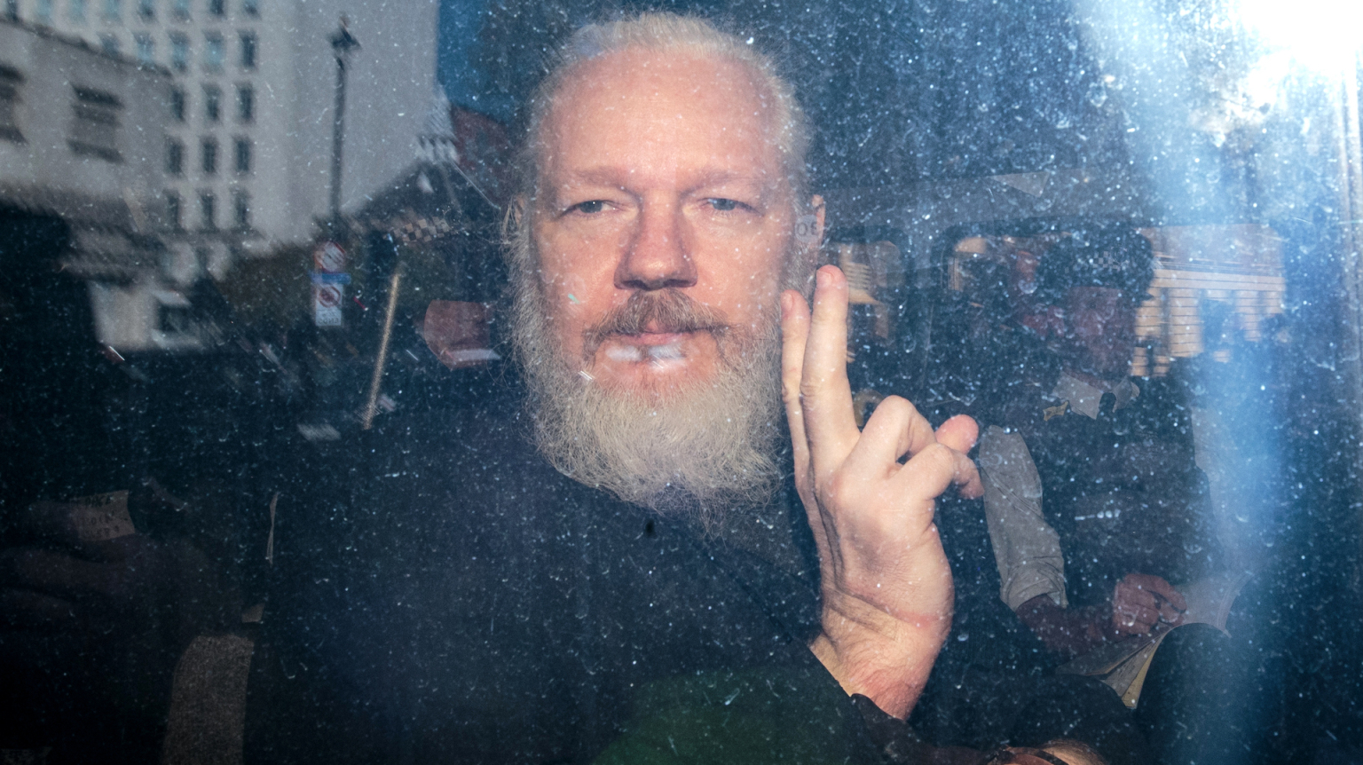 Julian Assange gestures to the media from a police vehicle on April 11, 2019 in London.