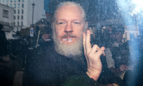 Julian Assange gestures to the media from a police vehicle on April 11, 2019 in London.