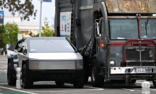 A Cybertruck parked next to a garbage truck