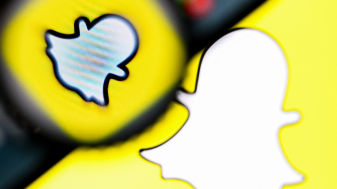 A snapchat logo with a magnifying glass and a phone hovering over it. 