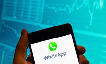 In this photo illustration, the encrypted instant messaging application owned by Meta Platforms and formerly known as Facebook, and WhatsApp, a logo is seen displayed on a smartphone with an economic stock exchange index graph in the background.