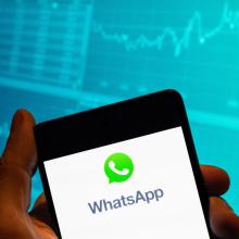 In this photo illustration, the encrypted instant messaging application owned by Meta Platforms and formerly known as Facebook, and WhatsApp, a logo is seen displayed on a smartphone with an economic stock exchange index graph in the background.