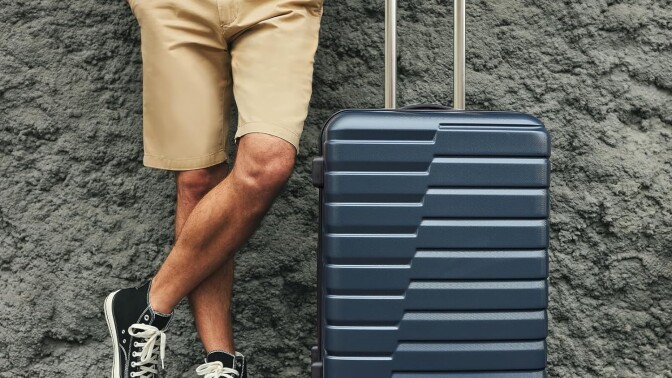 A man stands next to a suitcase