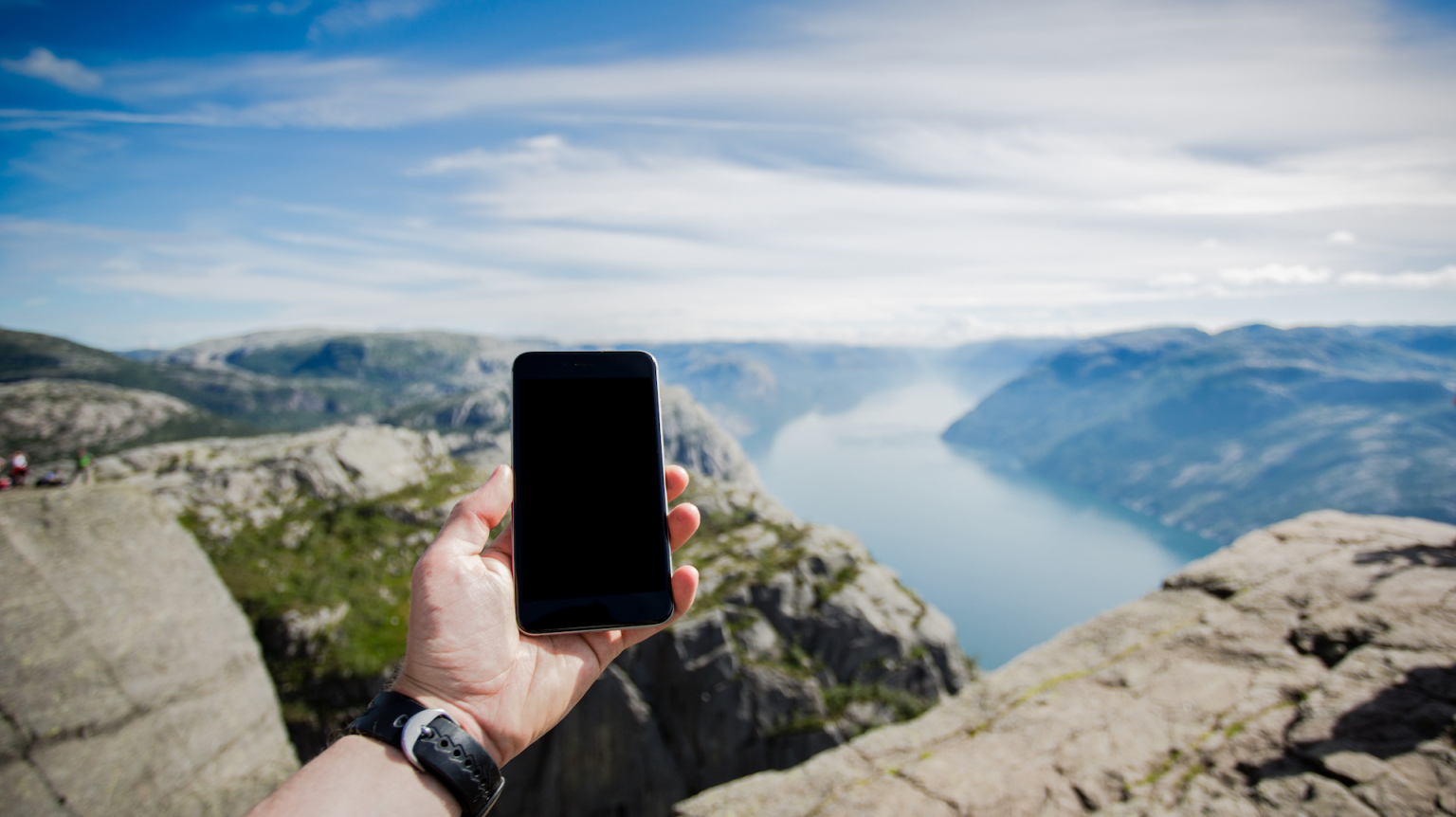 A person holds a phone up toward the horizon in a remote area.