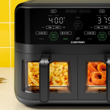 Chefman air fryer with fries and onion rings in baskets and other fried appetizers on counter beside it