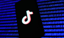 A phone showing the TikTok label in front of lines of binary code.