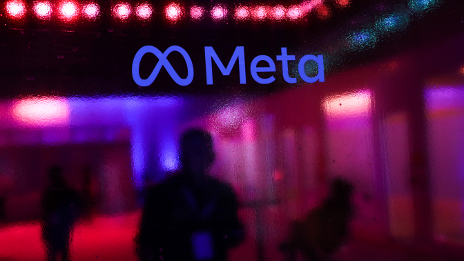 the Meta logo on a wall with a blurry reflected background