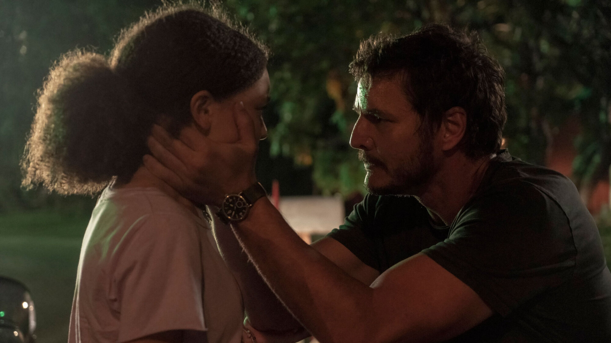 A man holds the face of a young girl as he stares at her.