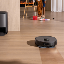 Eufy X9 Pro robot vacuum mopping hardwood floor with dock and family in background