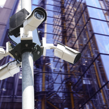 Several street surveillance cameras in front of a glass building.