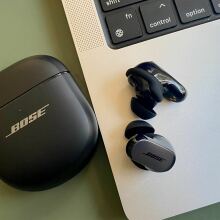 bose qc ultra earbuds on table next to macbook