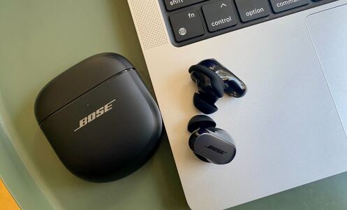 bose qc ultra earbuds on table next to macbook