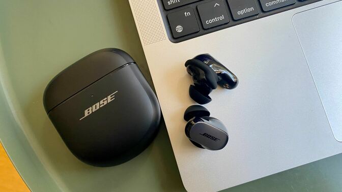 bose qc ultra earbuds on table next to macbook