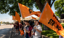 Community members hold up orange flags to remember the victims of the Robb Elementary shooting on Wednesday, May 24, 2023 in Uvalde, TX