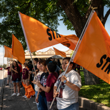 Community members hold up orange flags to remember the victims of the Robb Elementary shooting on Wednesday, May 24, 2023 in Uvalde, TX