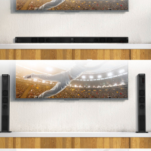 TV over shelf with two black vertical speakers on the bottom and one horizontal black speaker on top