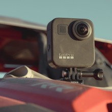 a GoPro Max camera sits mounted on the hood of a dusty car in the sun