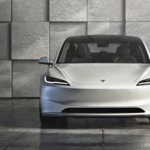 Tesla Model 3 sits in a modern, grey, concrete space.