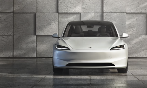 Tesla Model 3 sits in a modern, grey, concrete space.