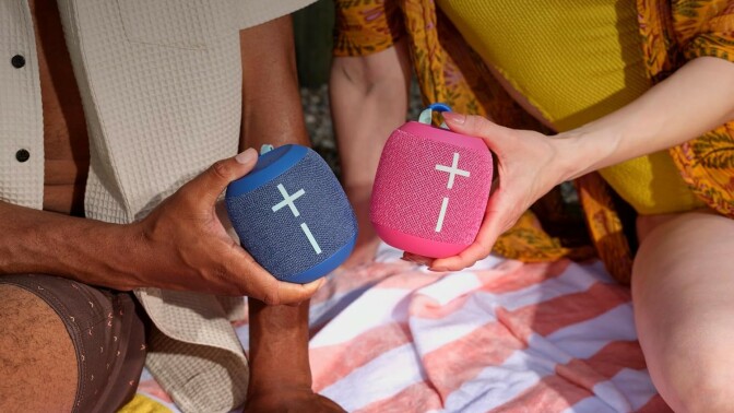 two people each hold an ultimate ears wonderboom 4 speaker while sitting on a picnic blanket