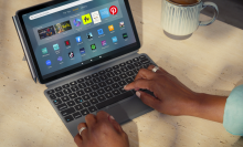 a close-up of a woman typing on an amazon fire 11 max tablet with a keyboard case and stylus attached