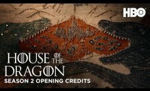 A tapestry of two dragons breathing fire over a castle and soldiers.