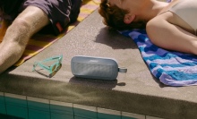 Person laying next to Bose Bluetooth speaker by the pool.