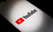 The YouTube logo is illuminated on a smartphone