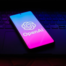 The OpenAI logo is displayed on a smartphone screen.