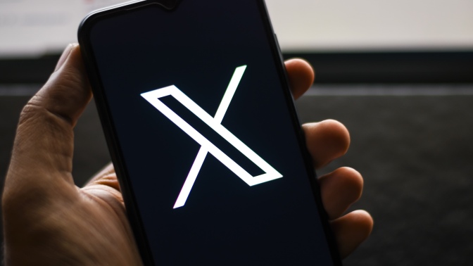 A person looks at X on their cell phone.