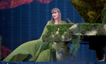 Taylor Swift sitting at a piano in a green dress. 