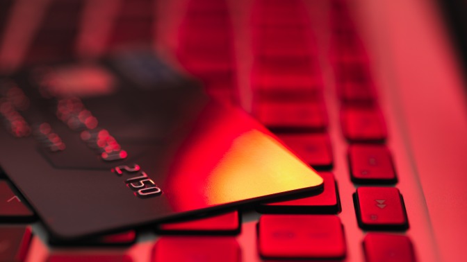 A credit card on a laptop under intense red lighting. 