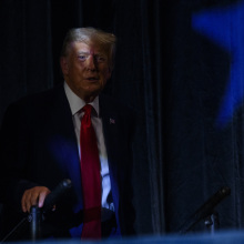 donald trump sitting on a dark stage