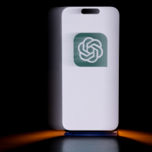 A phone displays a green OpenAI logo.