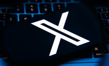 A close-up of a smartphone with the X logo on the screen.