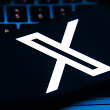 A close-up of a smartphone with the X logo on the screen.