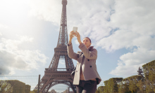 Female solo traveler make photo of Eiffel tower with smartphone while sightseeing in Paris