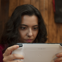 Woman holding the Logitech G Cloud gaming console in her hands while staring intensely at it 