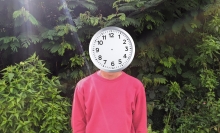 Person with a clock for a head in the woods