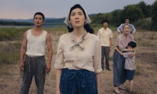 The Baek family stands in a brown field, looking up at the sky in worry.