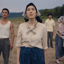 The Baek family stands in a brown field, looking up at the sky in worry.