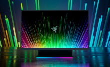 the razer raptor 27 against a shadowy rainbow background