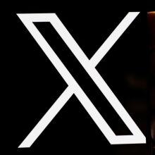 Hands holding a phone with the 'X' logo.