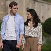 Robert and Yasmin walk through a garden.